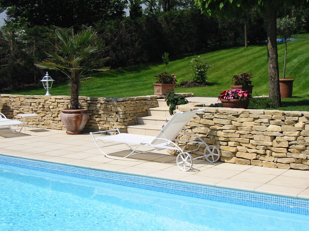 Piscine bordée de murets en pierre sèche et de pelouse