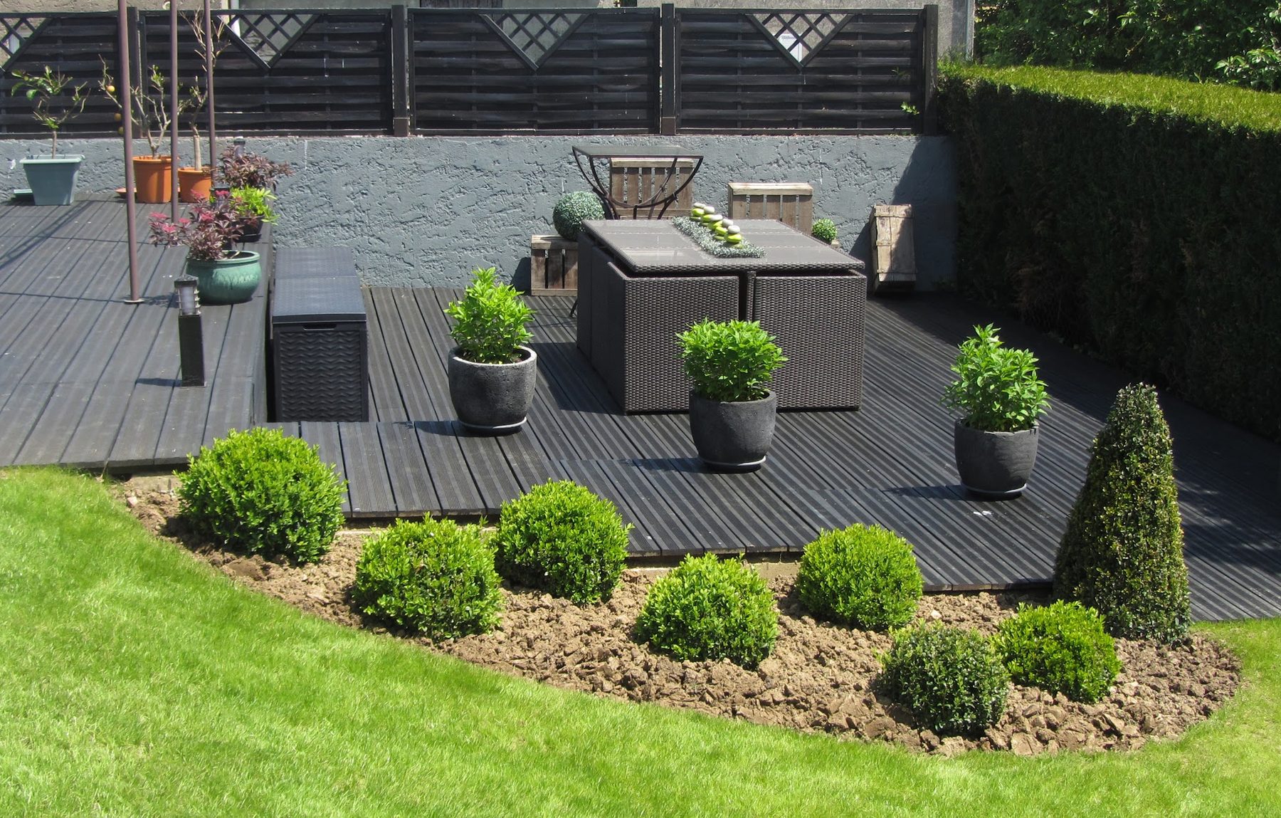 Terrasse en bois composite entourée de buis taillés