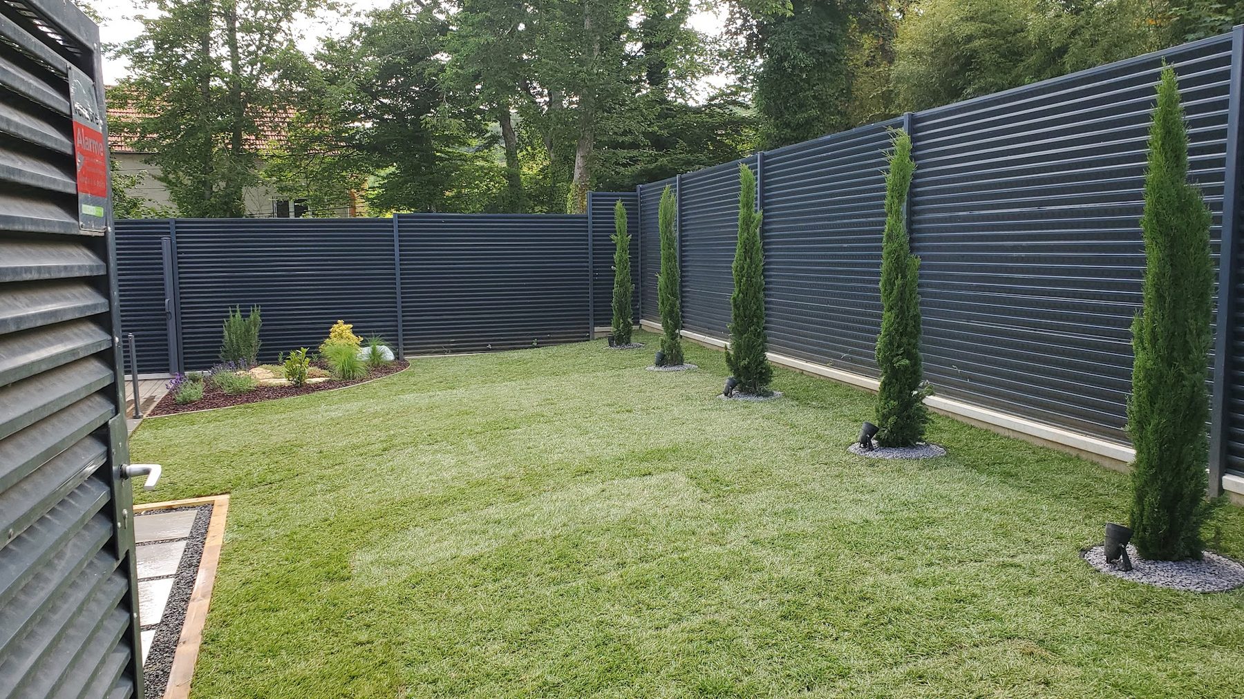 Jardin clos avec cyprès alignés le long d'une clôture