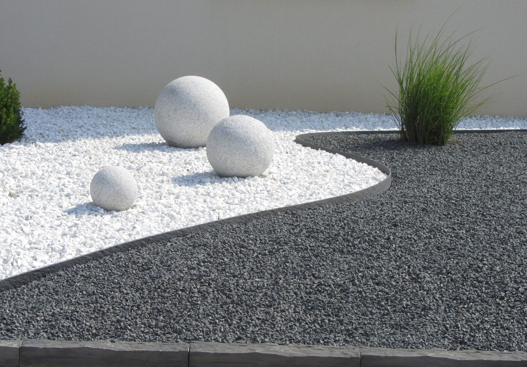 Jardin minéral aux galets blancs et gris avec sphères de pierre